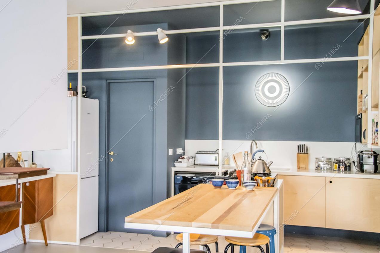Cucina con parete blu, isola in legno e pavimento in cemento lisciato e cementine bianche