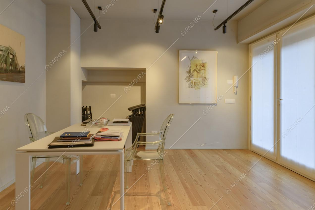 Studio con porta-finestra, scrivania bianca e pavimento in parquet
