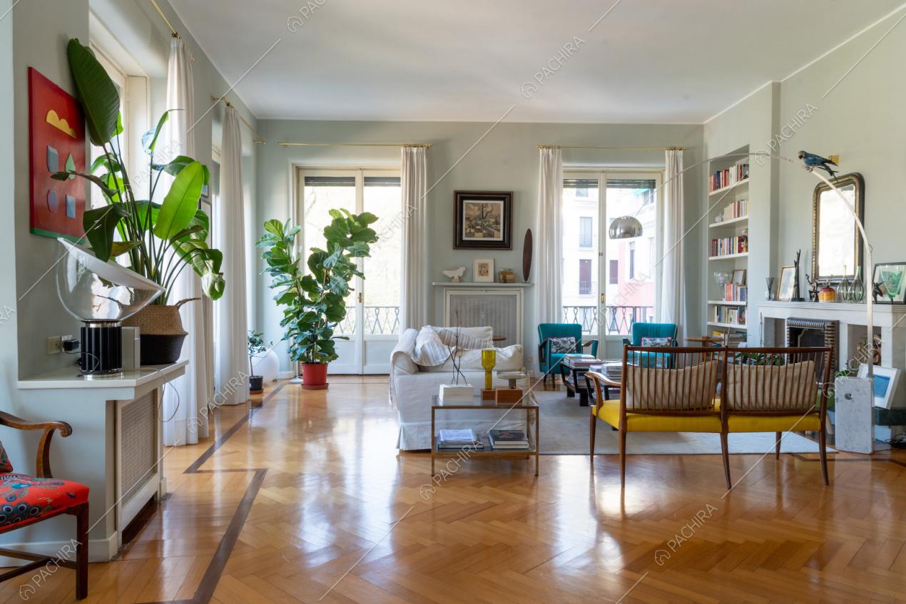 Luminoso salotto dal pavimento in parquet a spina di pesce con porte-finestre e camino