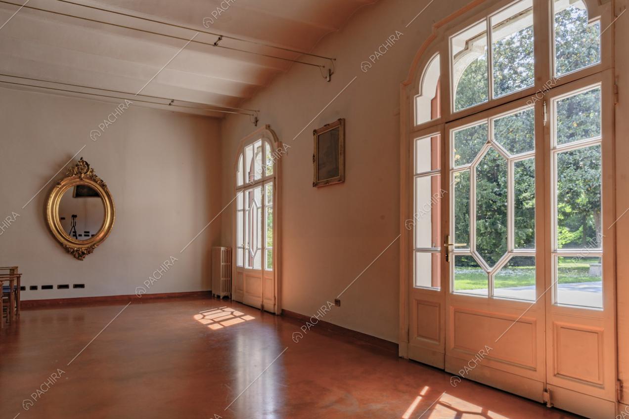 Ampia sale dalle pareti bianche con ampie porte-finestre bianche che si affacciano sul giardino privato