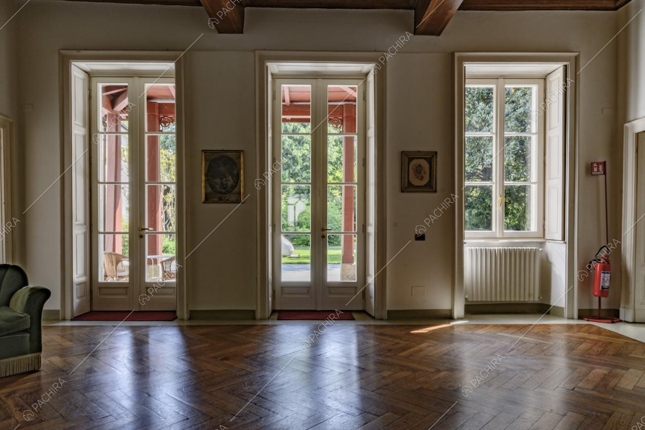Sala dalle pareti bianche illuminata dalle porte-finestre bianche che si affacciano sulla veranda