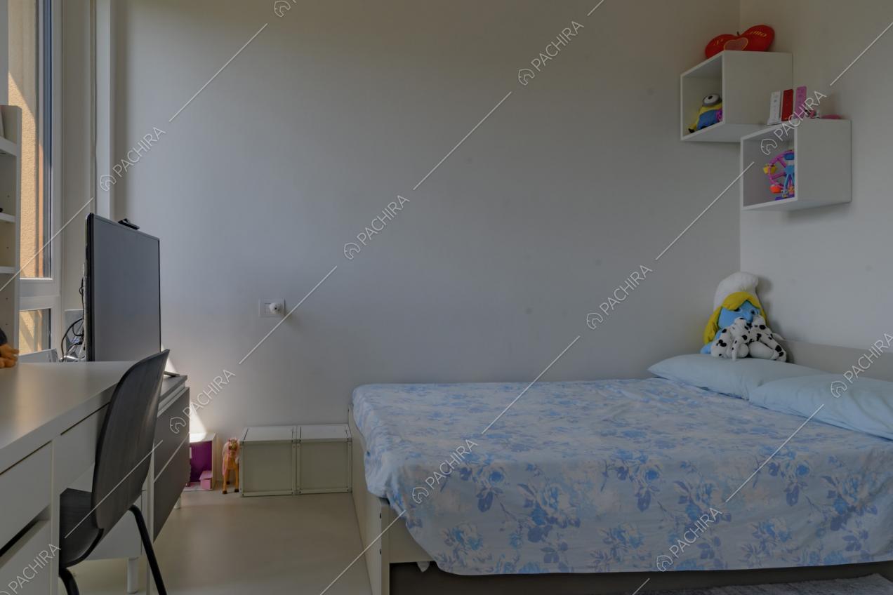 Camera da letto da bambini con pareti e scrivania bianche e pavimento in cemento lisciato