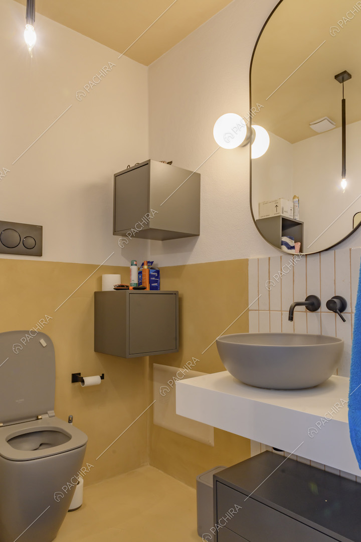 Bagno con pareti bianche e gialle e piastrelle rettangolari bianche