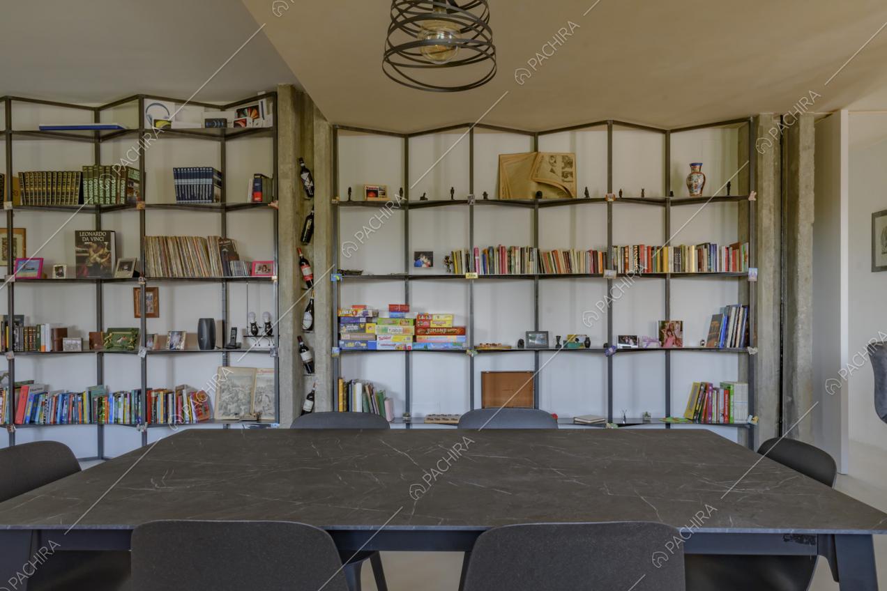 Tavolo da pranzo in marmo nero nella sala con libreria e lampadario di design