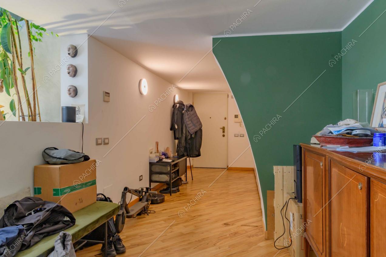 Atrio con pavimento in parquet, parete verde scuro e vista sulla porta d'ingresso