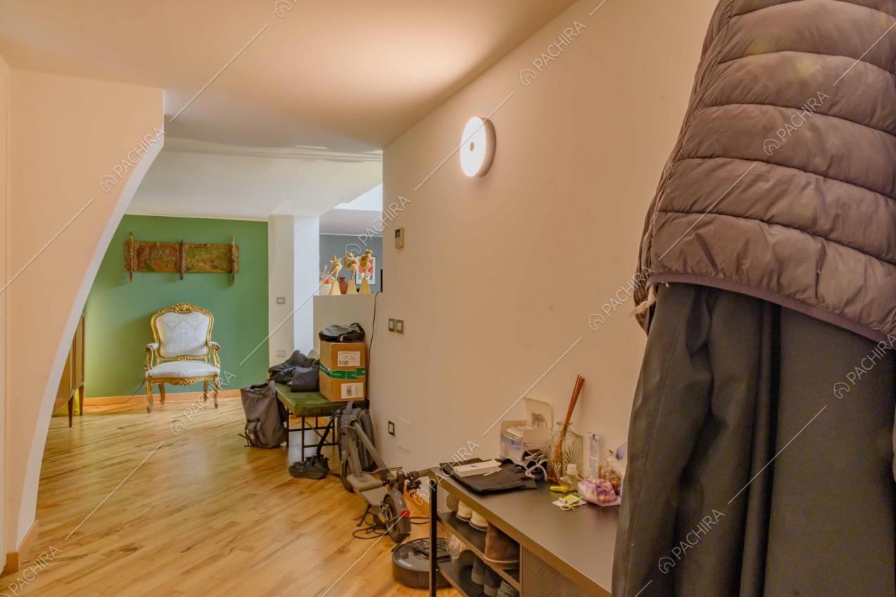 Dalla porta d'ingresso pavimento in parquet, parete verde e scorcio sulla cucina