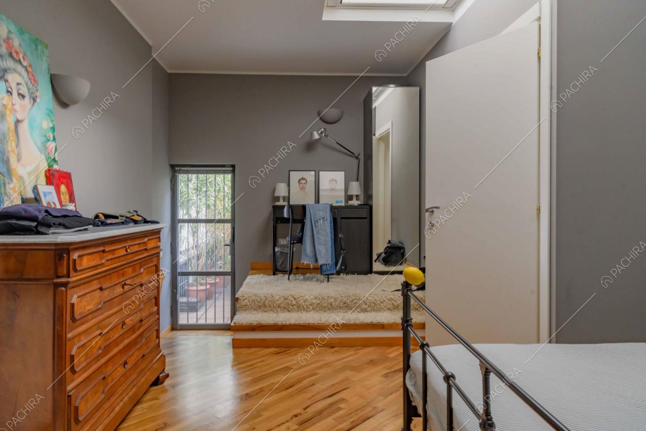 Camera da letto matrimoniale con pavimento in parquet, lucernario e accesso alla terrazza