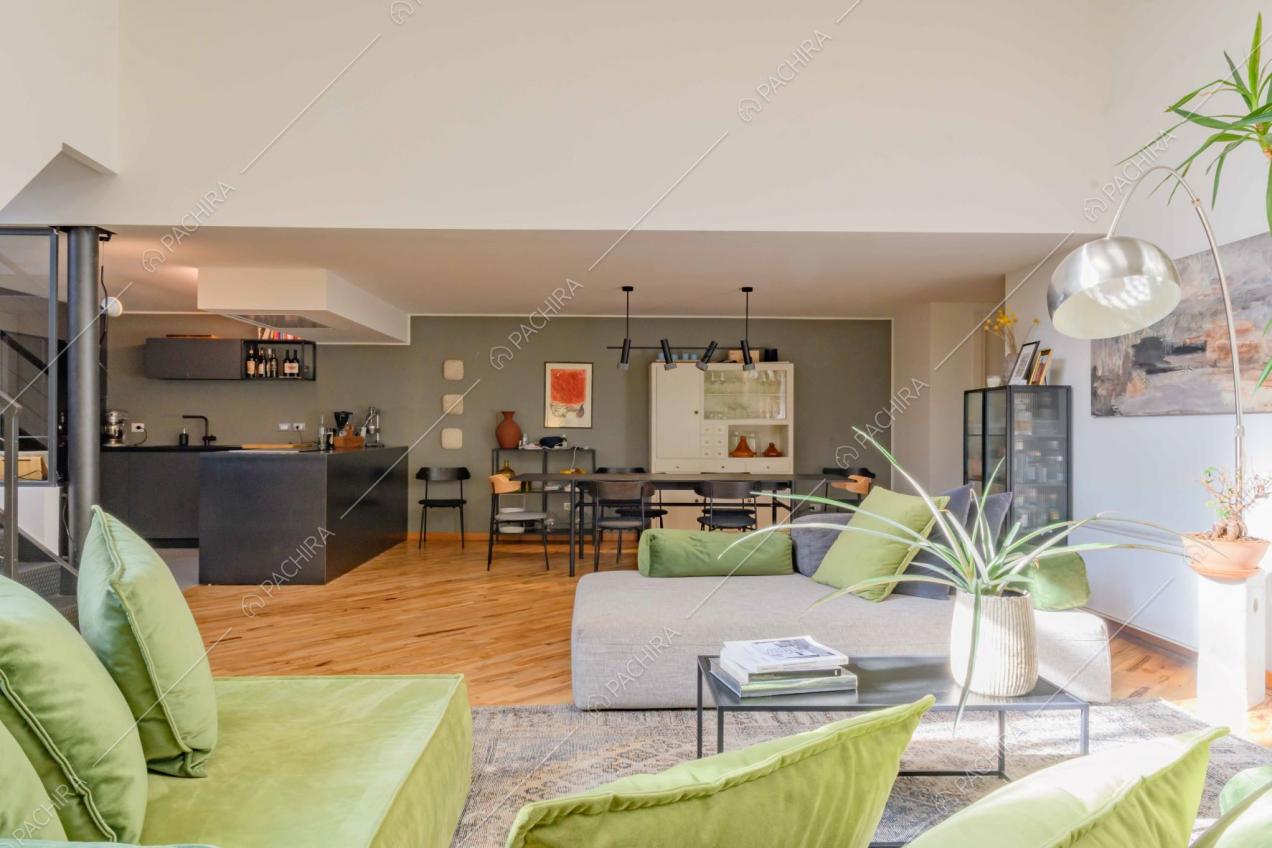 Zona living con divano verde, divano grigio e cucina a vista
