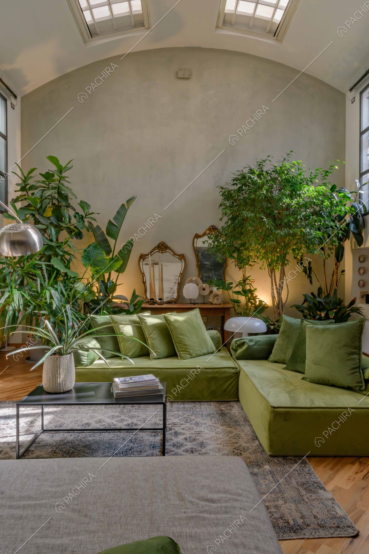 Luminoso salotto con piante, divano verde e pavimento in parquet