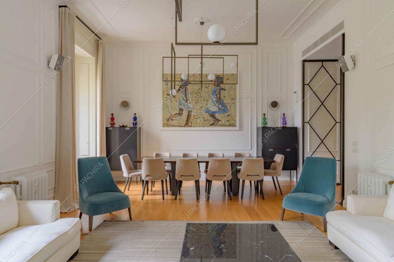 Vista dai divani bianchi sul tavolo da pranzo del soggiorno con pavimento in parquet