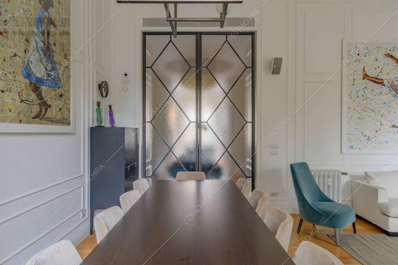 Tavolo da pranzo nero nel salotto con boiserie alle pareti e porta a vetri