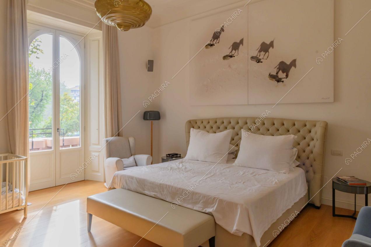Camera da letto matrimoniale con pavimento in parquet, pareti bianche e balcone