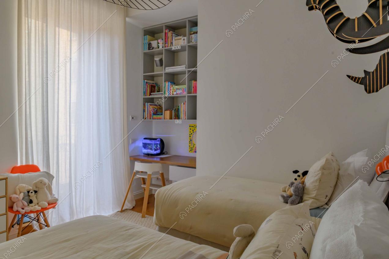 Camera da letto da bambini dalle pareti bianche e con due letti singoli