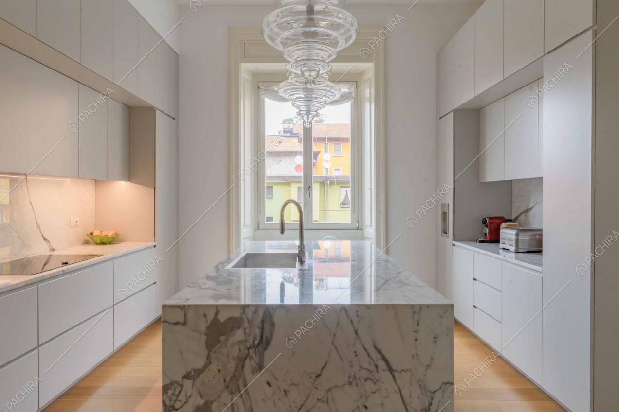 Cucina con isola in marmo, fornelli a induzione e pavimento in parquet