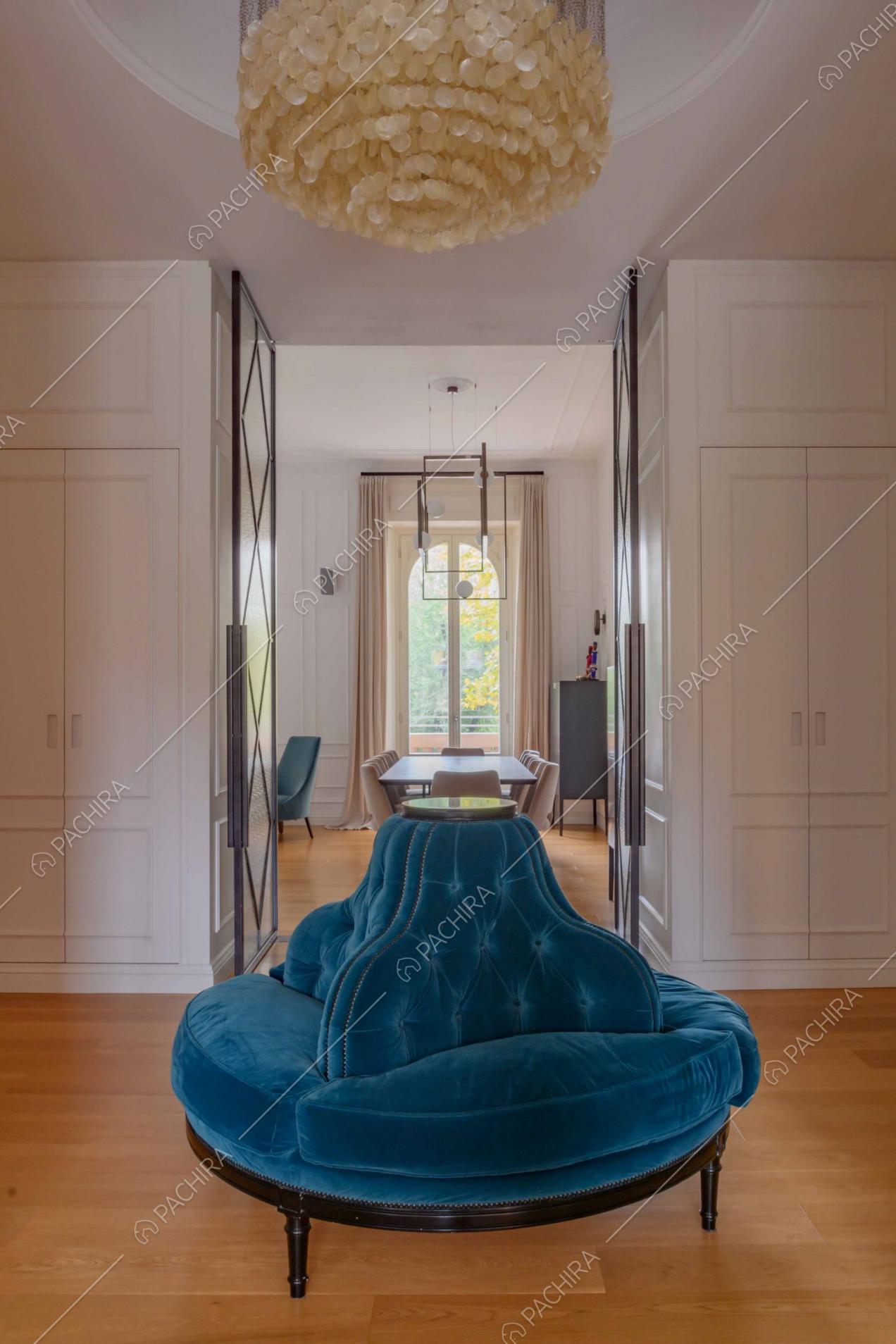 Poltrona di velluto blu di design nell'atrio e vista sul tavolo da pranzo del soggiorno