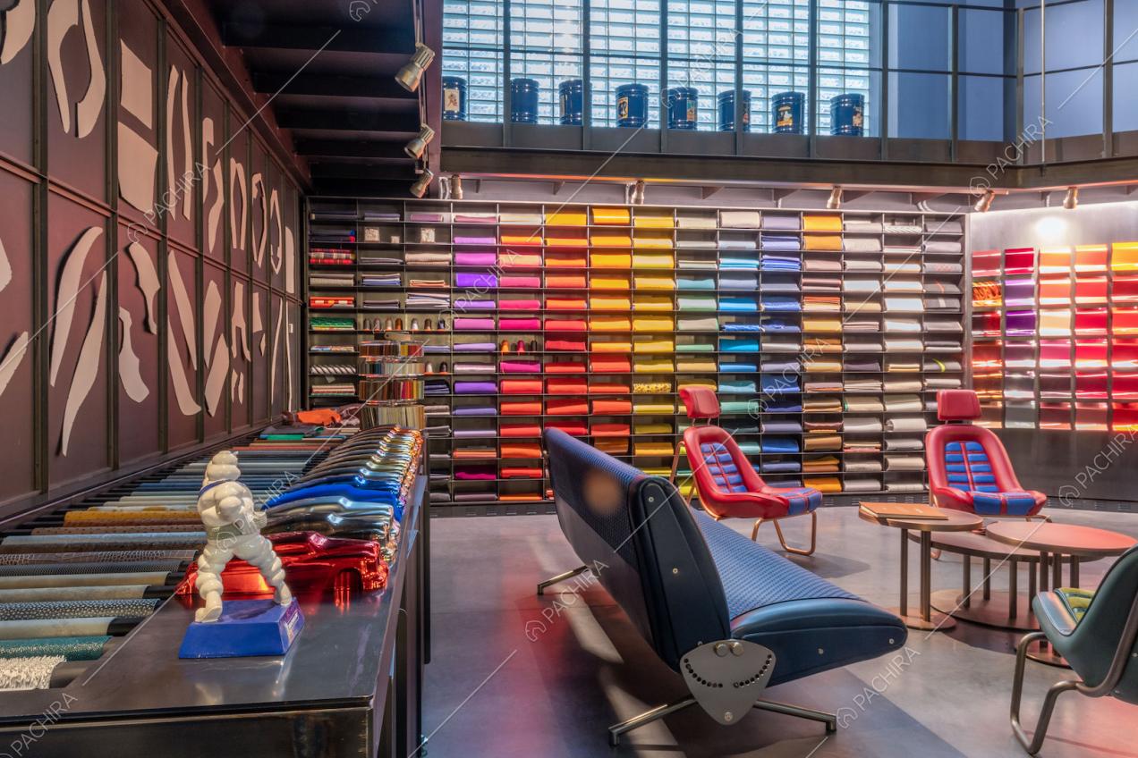 Ripiani con tessuti e colori diversi nella stanza con poltrone e divano di design colorati