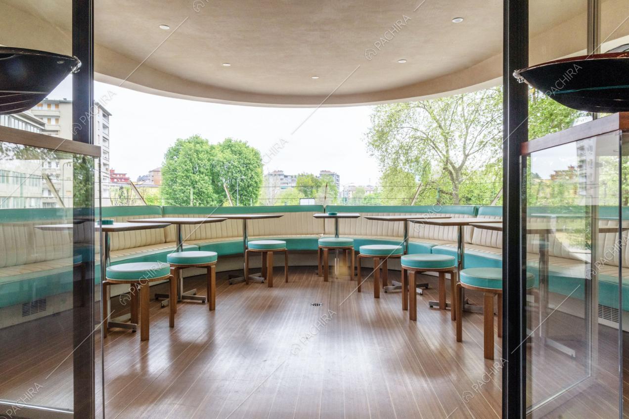 Terrazza coperta con vista sulla città, panca in pelle bianca e verdeacqua e tavolini
