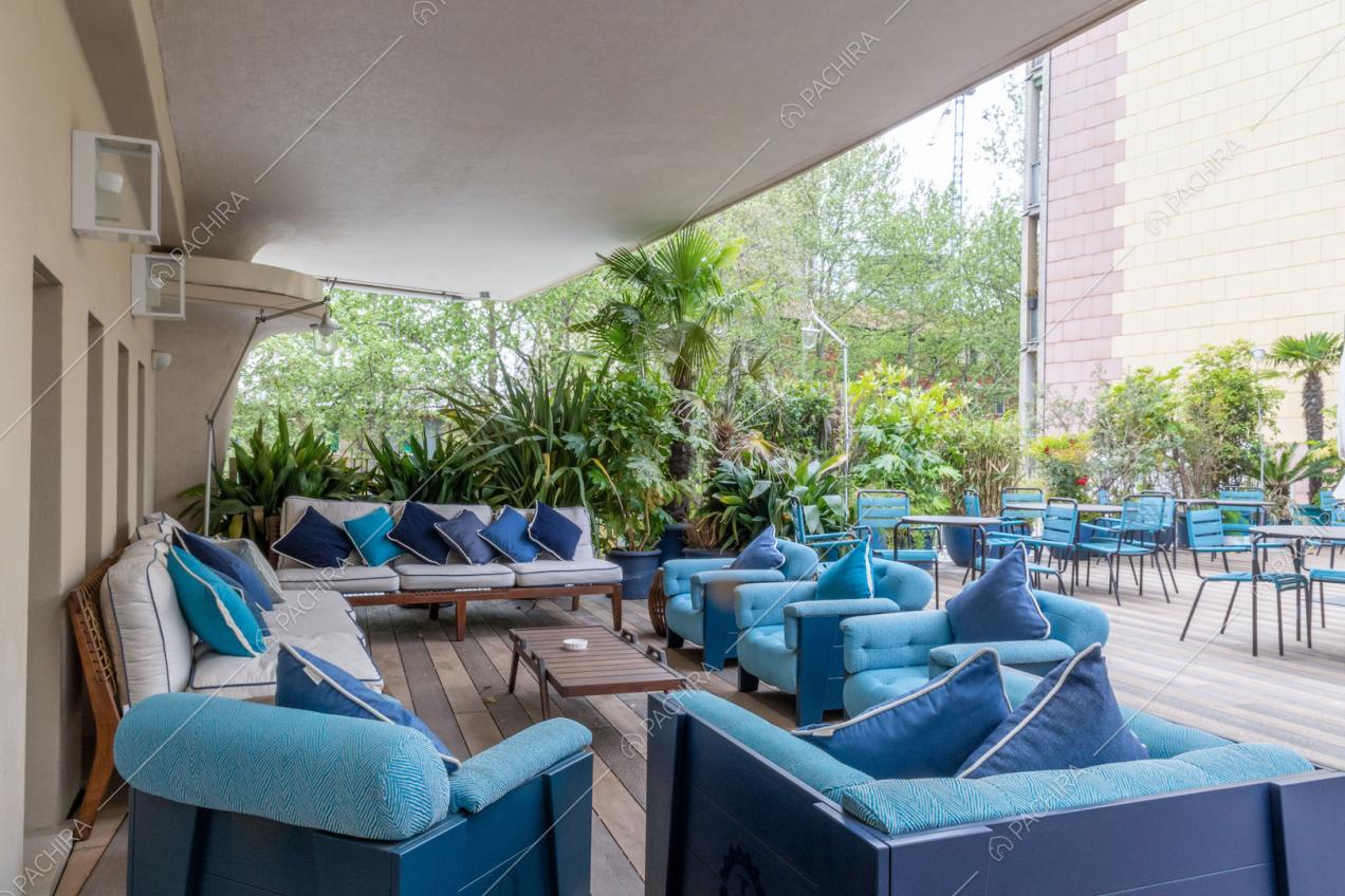 Grande terrazza con pavimento in parquet, divanetti e sedie blu