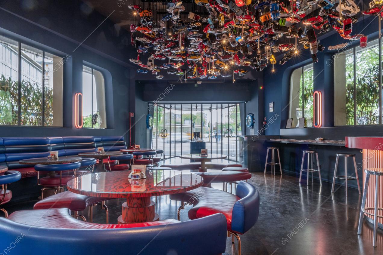 Divani rossi con schienale blu nella sala con lampadario di design e grandi vetrate