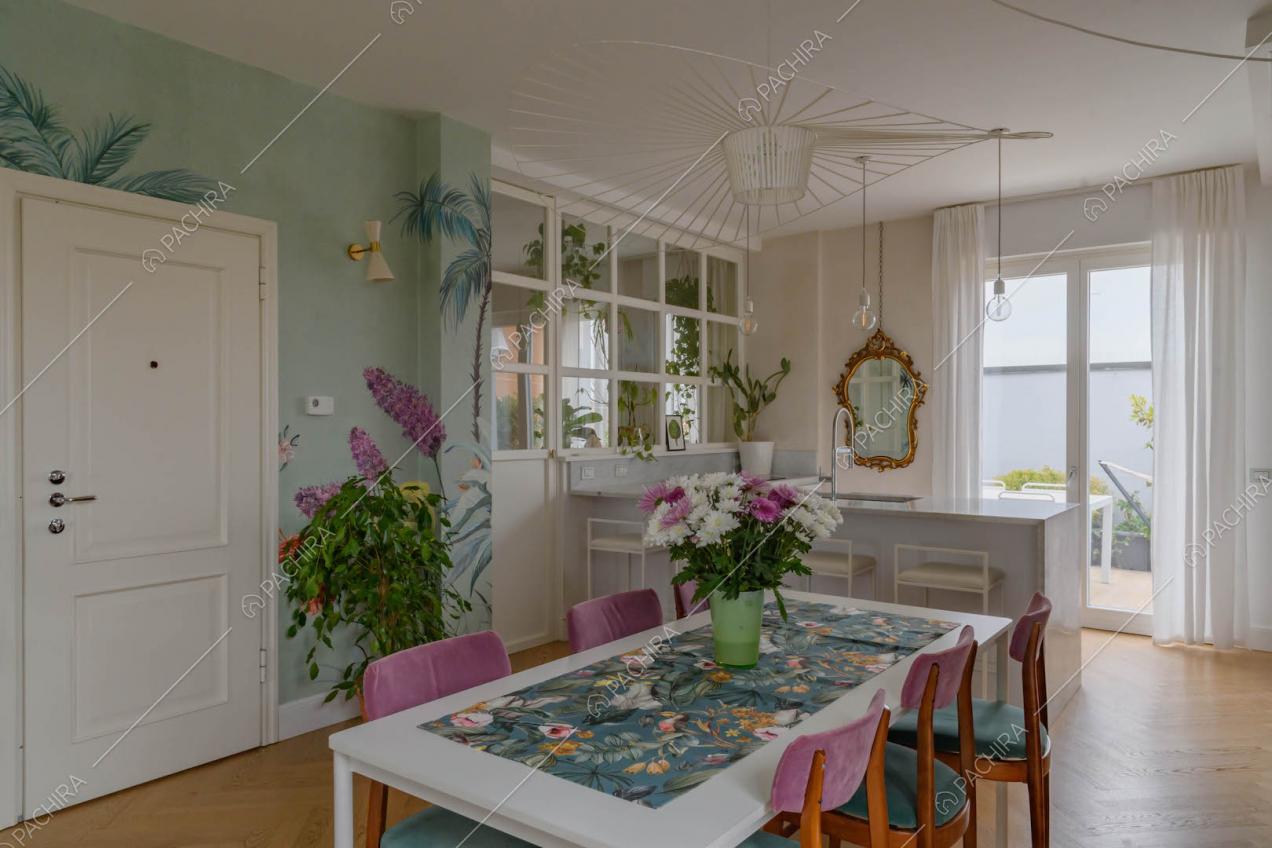 Tavolo da pranzo nell'open space con pavimento in parquet a spina di pesce e carta da parati