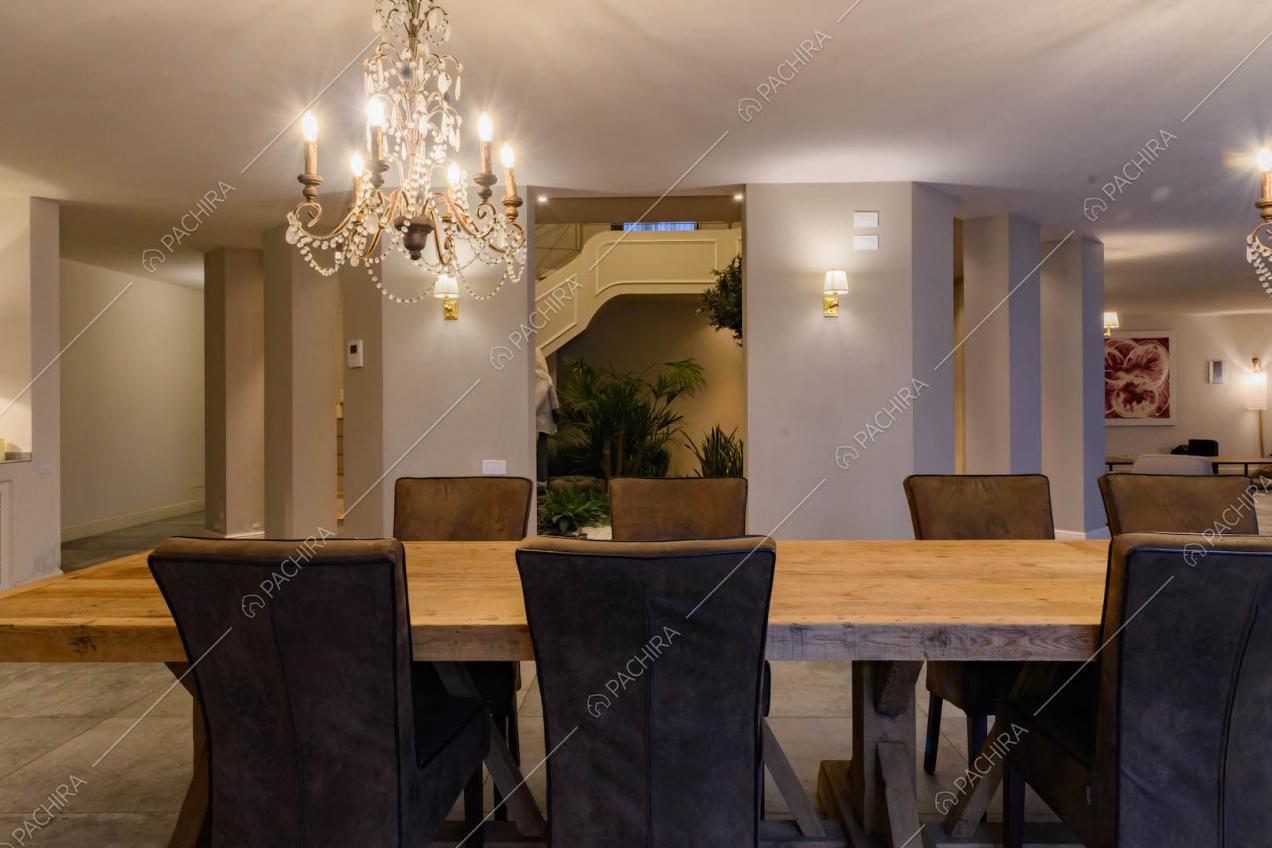 Sala da pranzo con lampadari in stile classico, tavolo in legno e vista sul giardino d'inverno