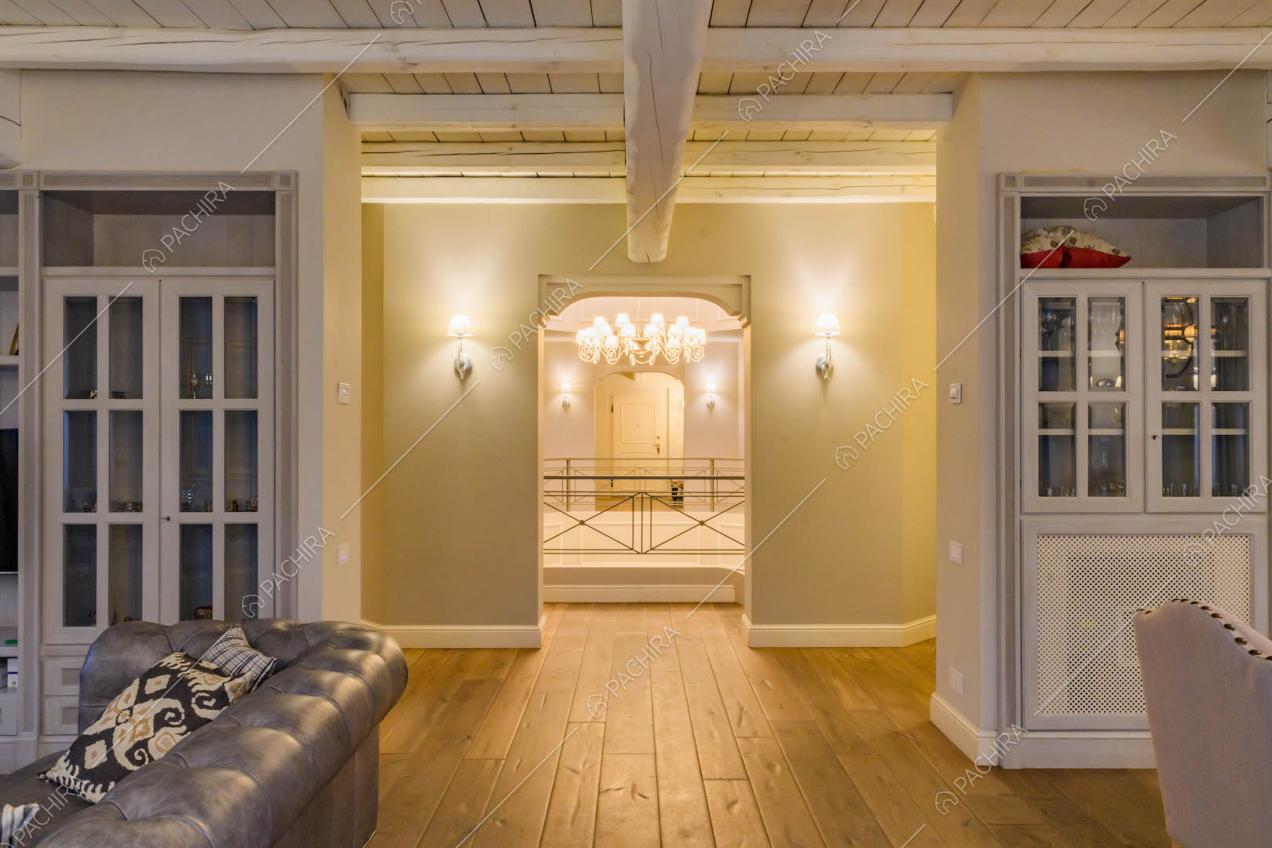 Sala con soffitto in travi in legno a vista, pavimento in parquet e vista sulle scale