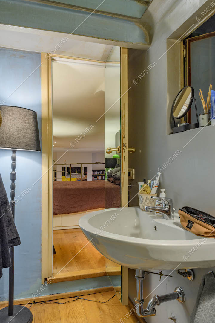 Dal lavandino del bagno con parete azzurra vista sul letto matrimoniale