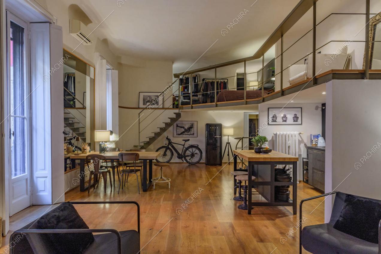 Poltrone nere di design nella luminosa sala con porte-finestre e soppalco