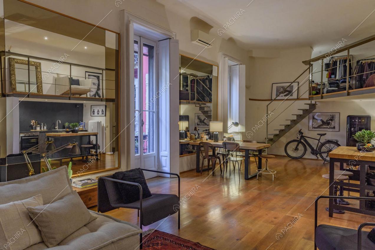 Sala con pavimento in parquet, grande specchio e soppalco