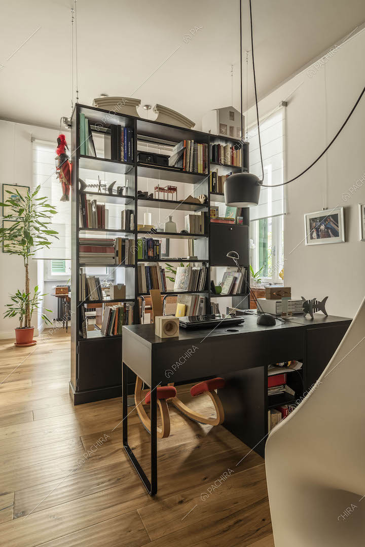 Scrivania nera nell'ingresso con pavimento in parquet e poltrona bianca di design a forma di visto
