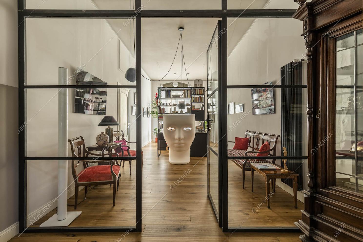 Ingresso della location con pavimento in parquet e parete in vetro e metallo nero