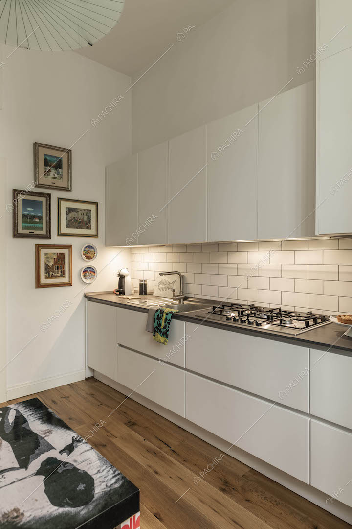 Cucina a parete con fornelli a gas, pareti bianche e pavimento in parquet