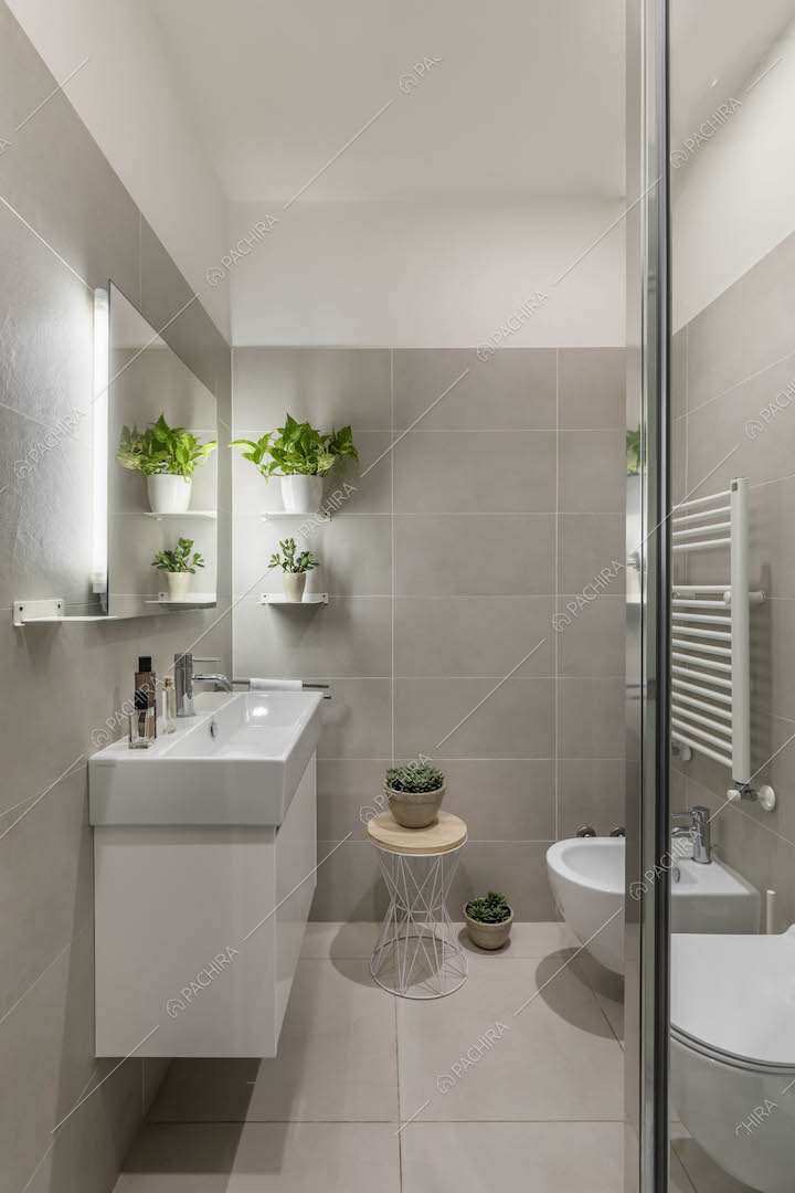Bagno con mobile sospeso e piastrelle grigie su pareti e pavimento