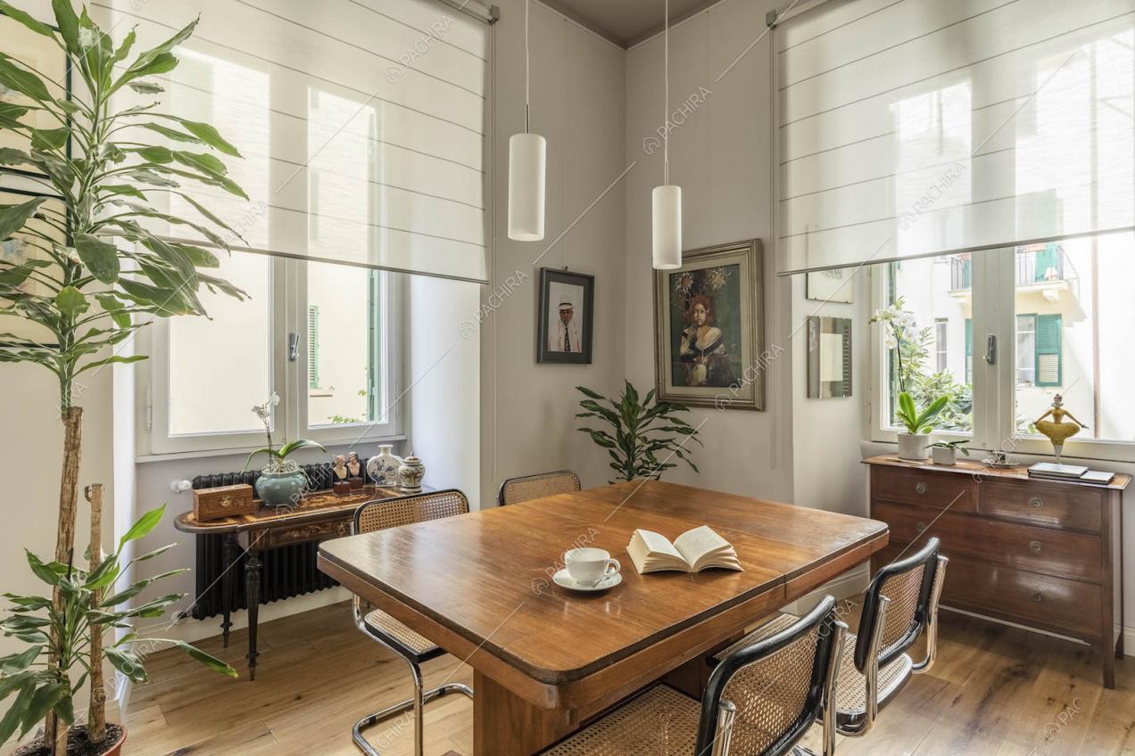 Tavolo da pranzo e sedie vintage nella sala con ampie finestre e pavimento in parquet