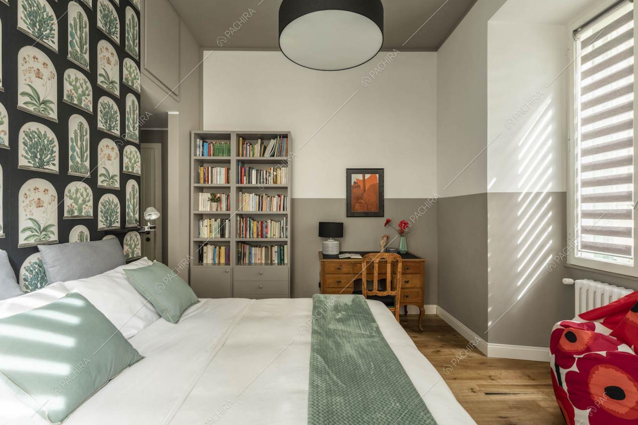 Camera da letto matrimoniale con soffitto grigio, pavimento in parquet e libreria