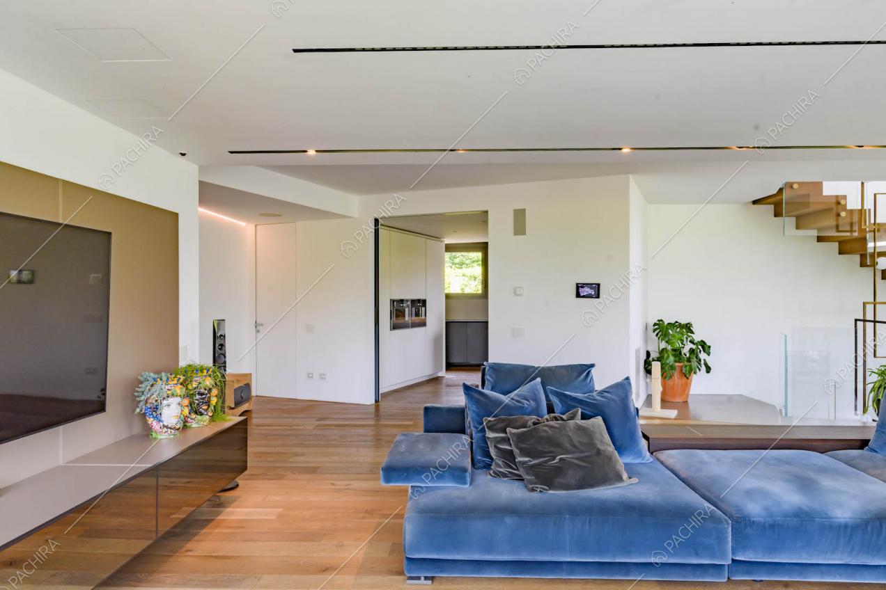 Divani blu nella sala con pareti bianche, pavimento in parquet e vista sulla cucina a isola