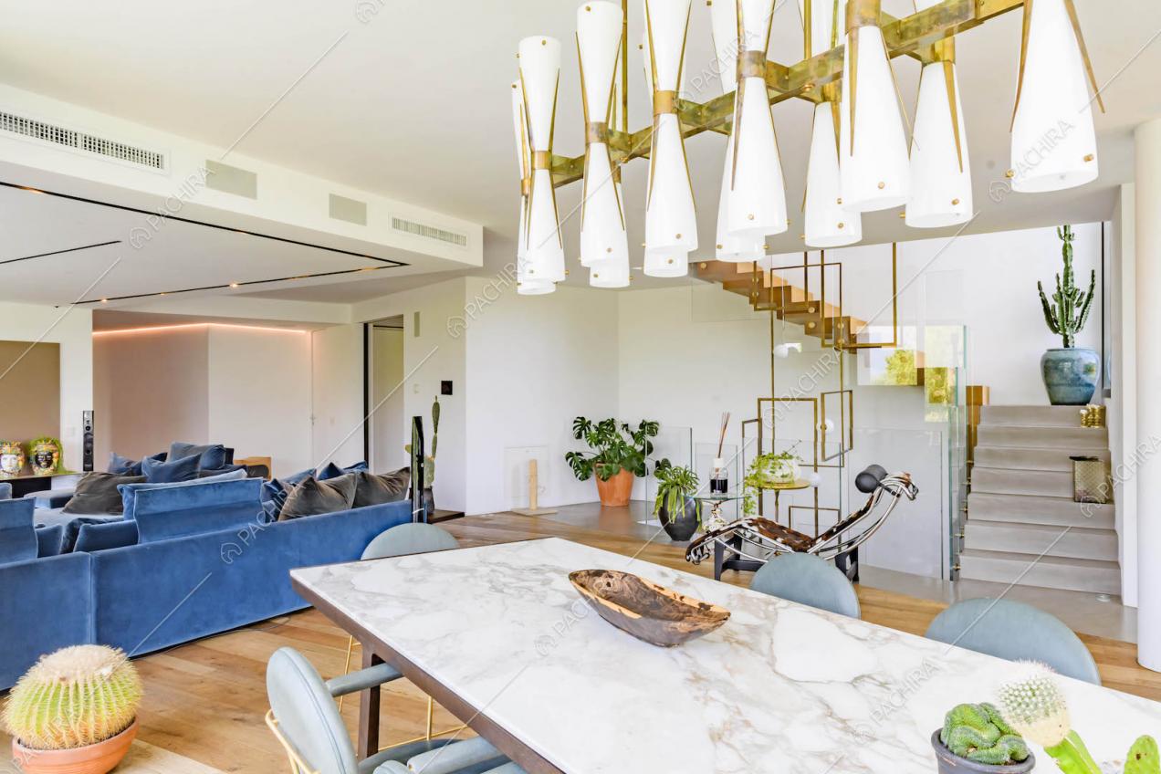 Tavolo da pranzo con piano in marmo nella sala con divani blu e scale