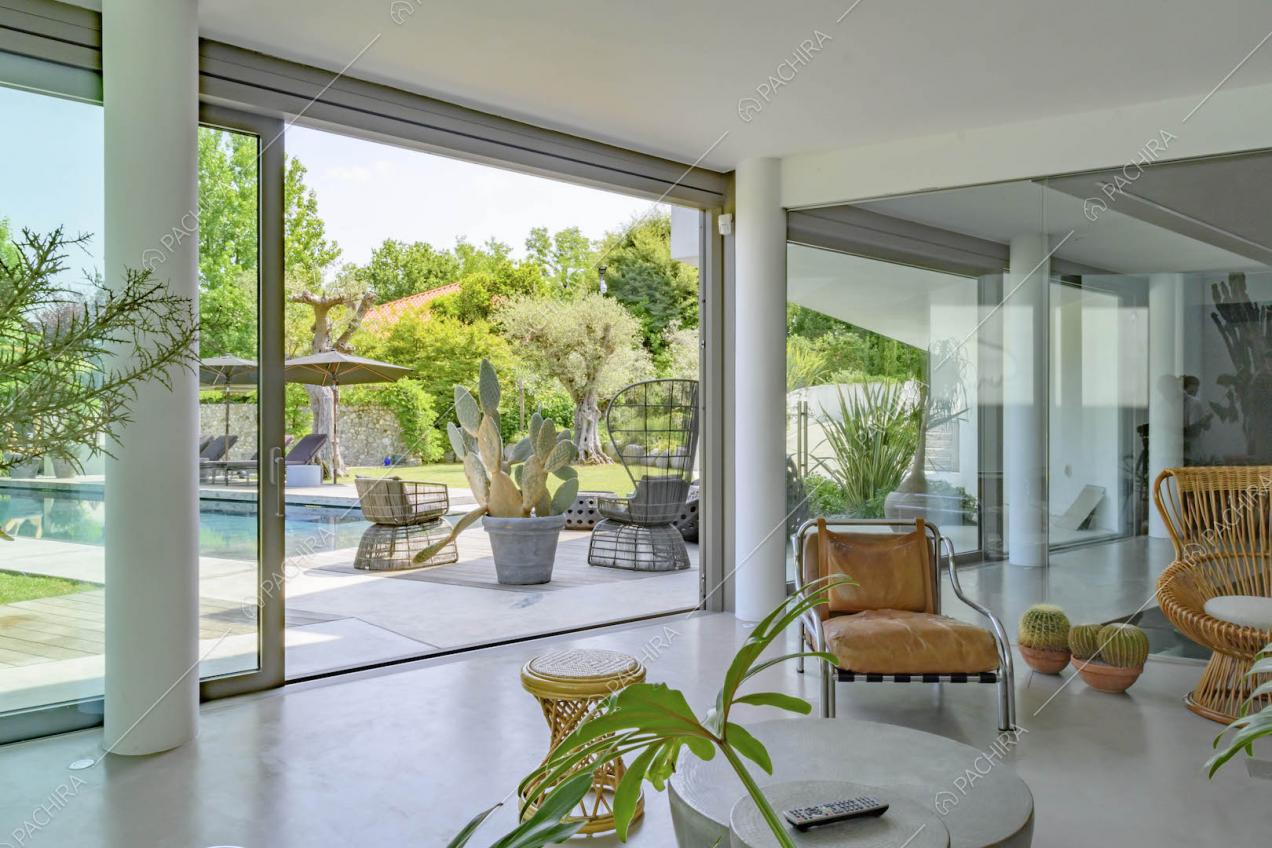 Dal divano di design vista sul giardino con piscina tramite la grande porta-finestra scorrevole in vetro