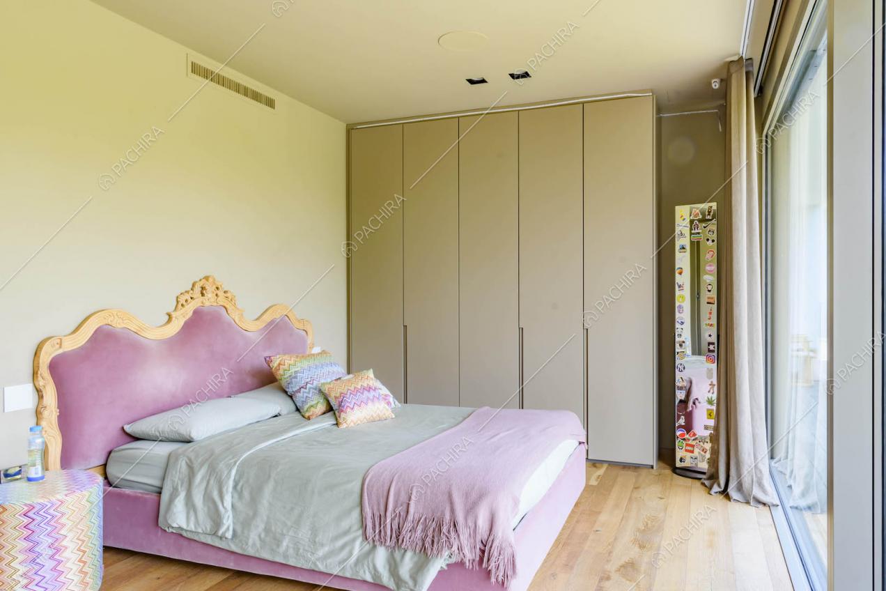 Luminosa camera da letto matrimoniale con struttura in velluto rosa e pavimento in parquet