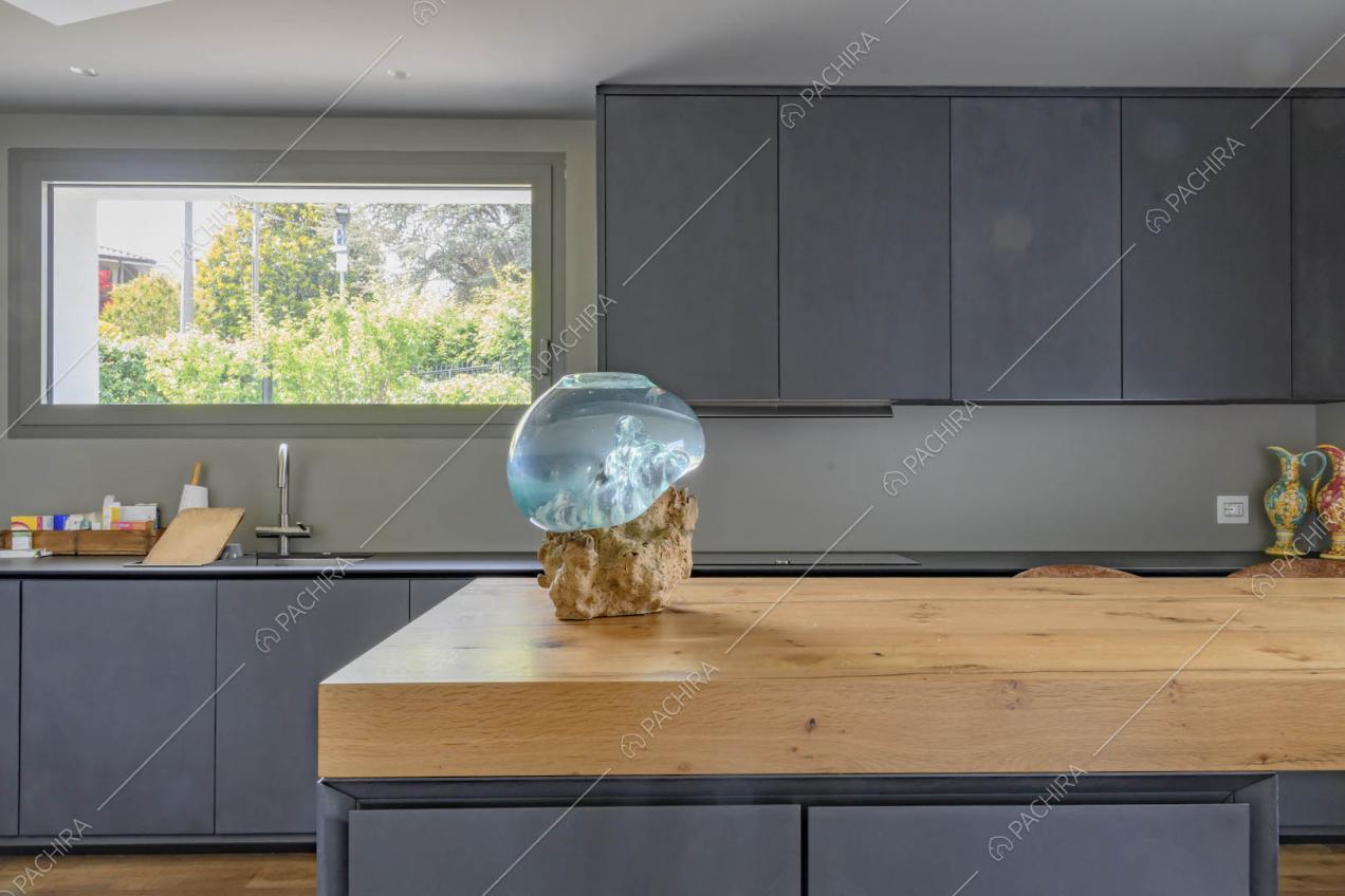Piano da lavoro in legno dell'isola nella luminosa cucina con pavimento in parquet