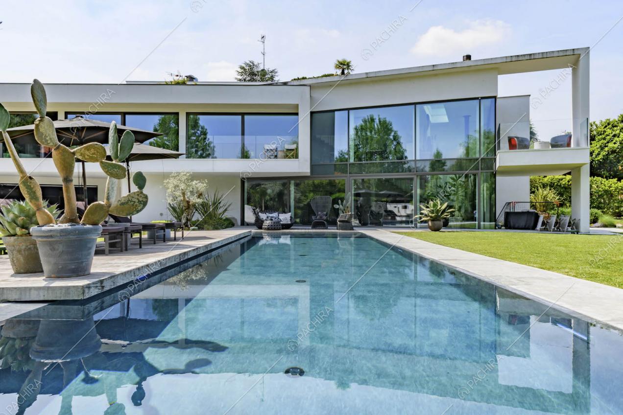 Dalla grande piscina nel giardino vista sulla location con grandi vetrate e veranda