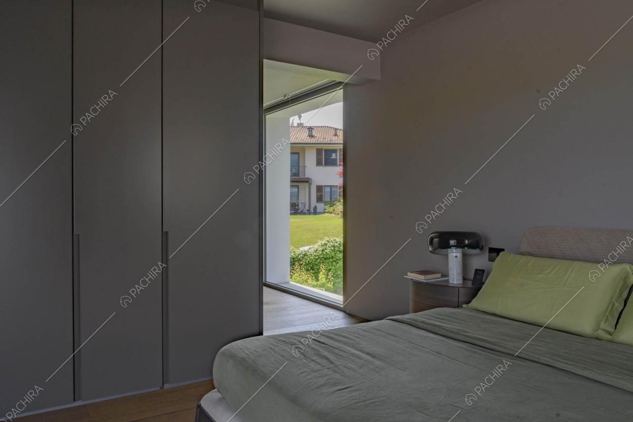 Letto matrimoniale nella camera con armadi a muro, pavimento in parquet e pareti grigie