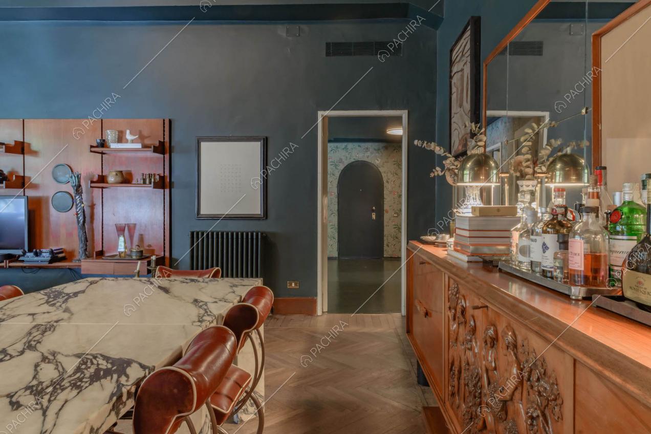 Dal tavolo da pranzo in marmo con sedie rosse di design vista sul corridoio con carta da parati