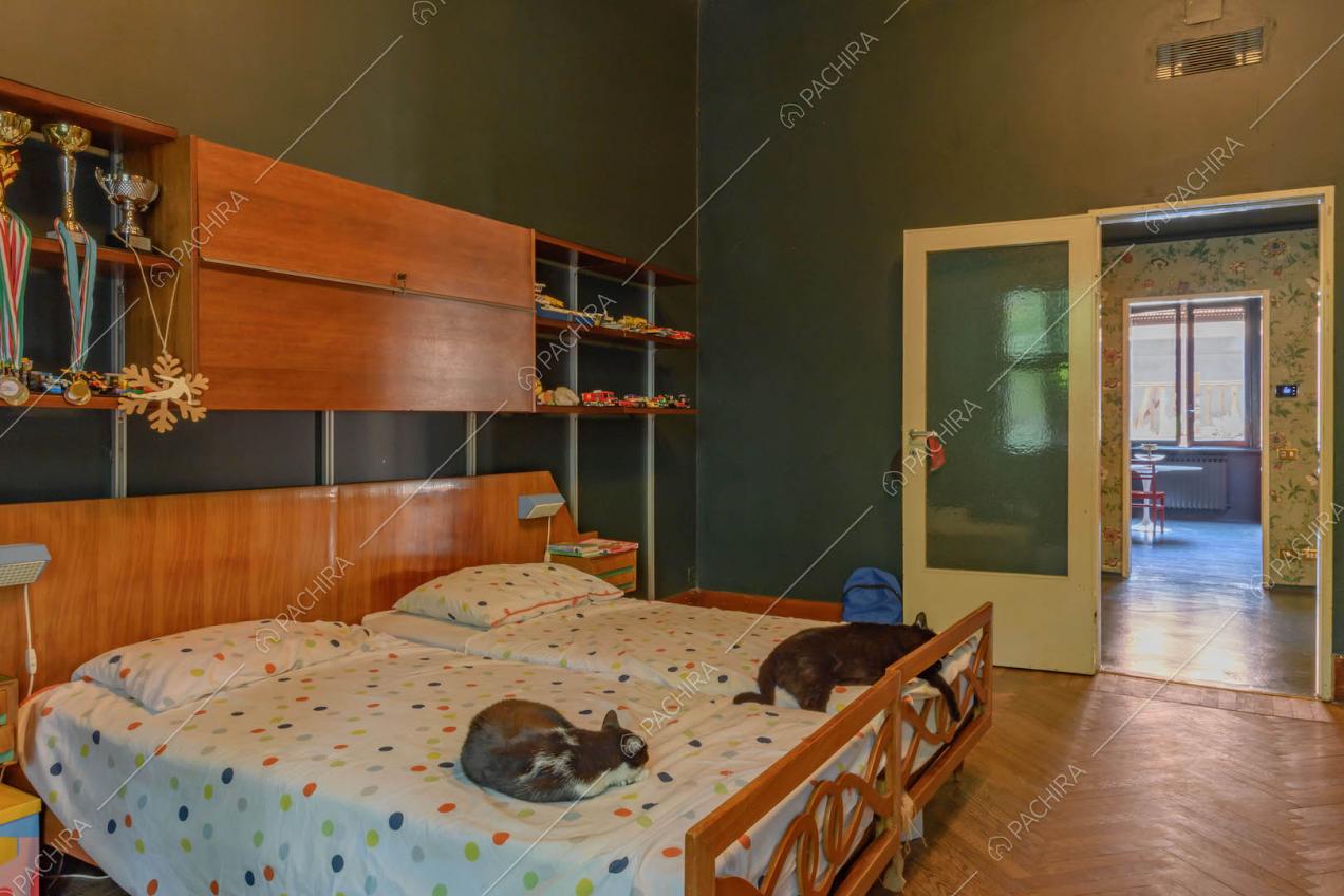 Letto matrimoniale nella camera con pavimento in parquet e vista sulla cucina