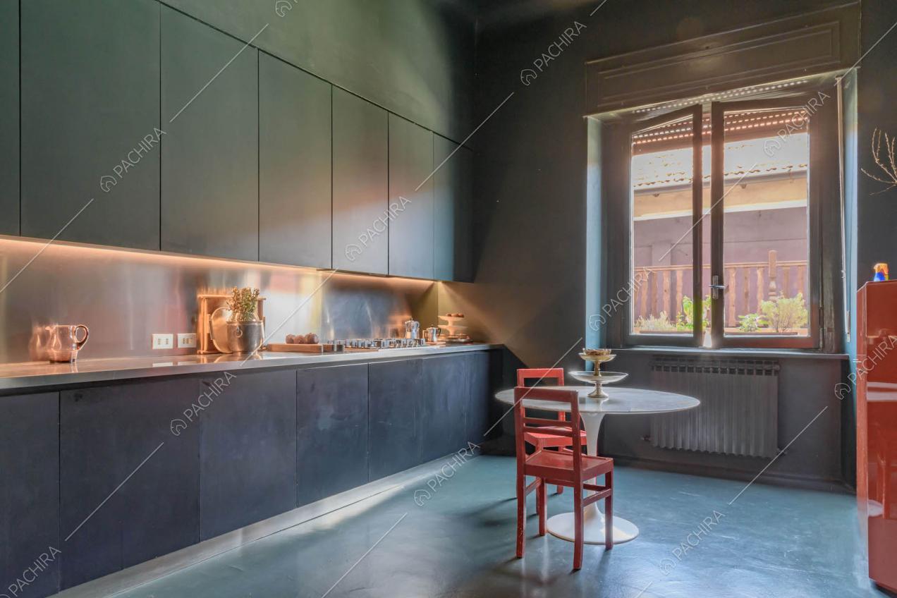 Cucina total blue a parete con fornelli a gas e tavolo da pranzo in marmo con sedie rosse