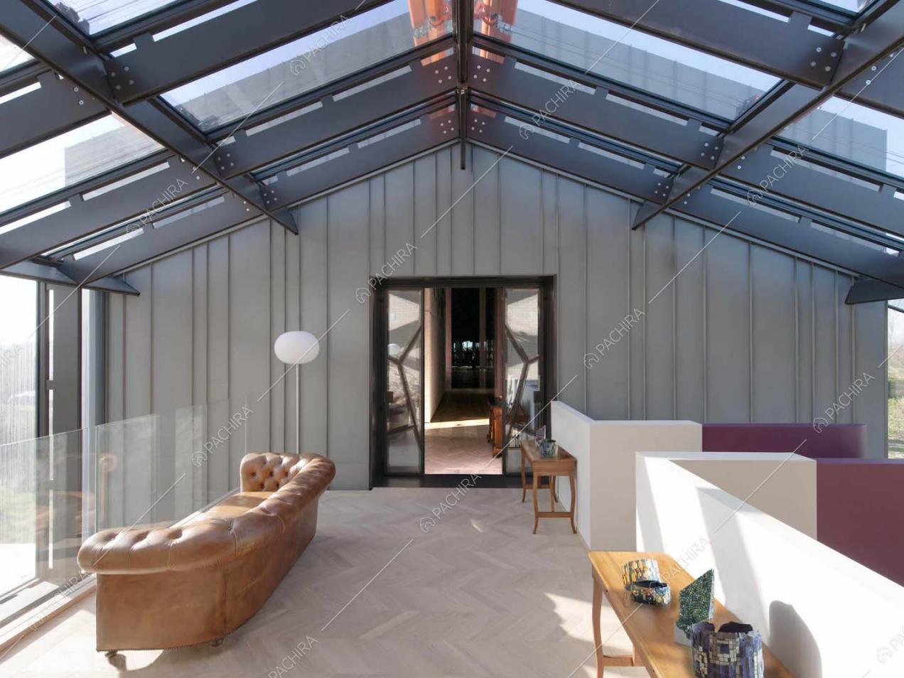 Solaio con pareti e soffitto in vetro con infissi neri e pavimento in parquet a spina di pesce
