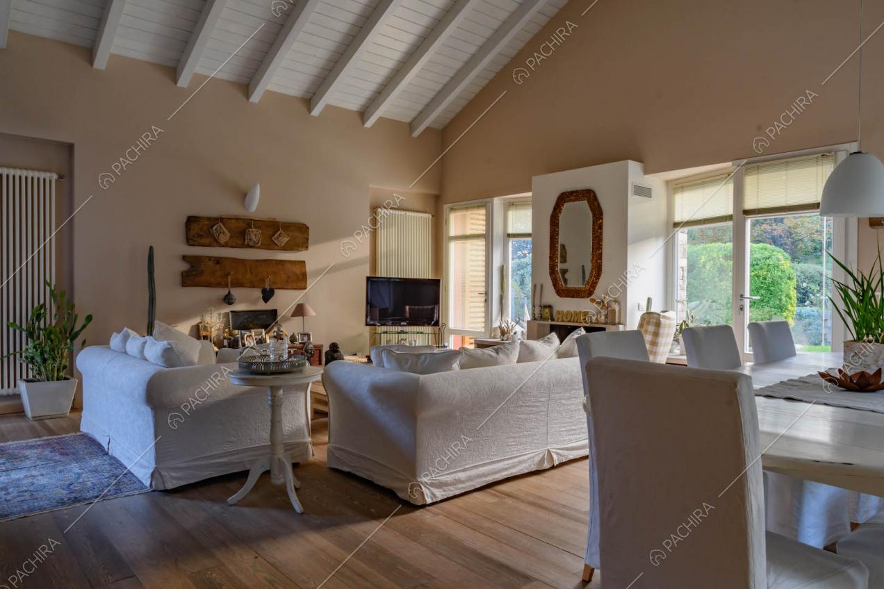 Tavolo da pranzo con sedie bianche nella zona living con travi bianche in legno a vista sul soffitto