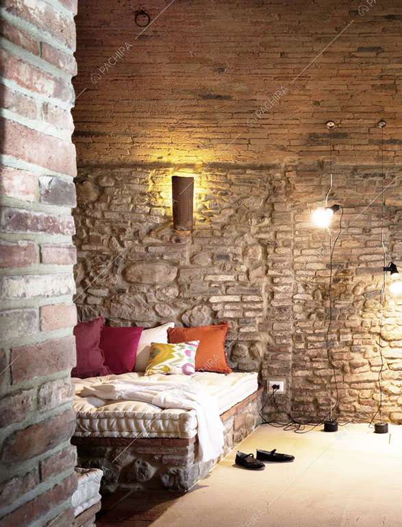 Pareti in mattoni e pietra a vista nella camera da letto matrimoniale