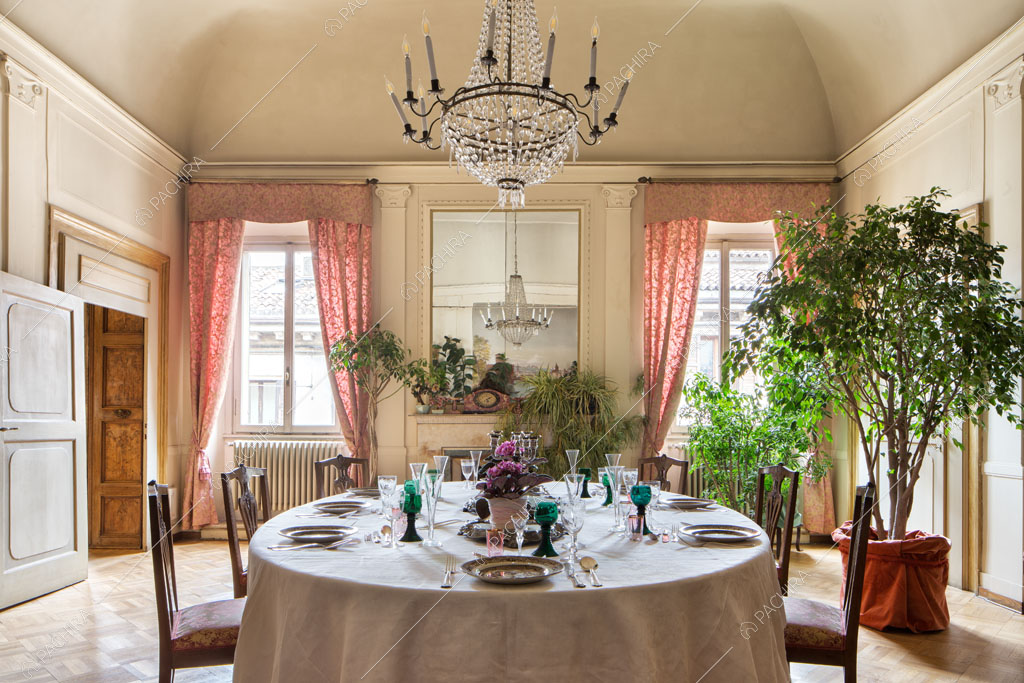 Tavolo da pranzo rotondo nella sala con boiserie alle pareti e pavimento in parquet