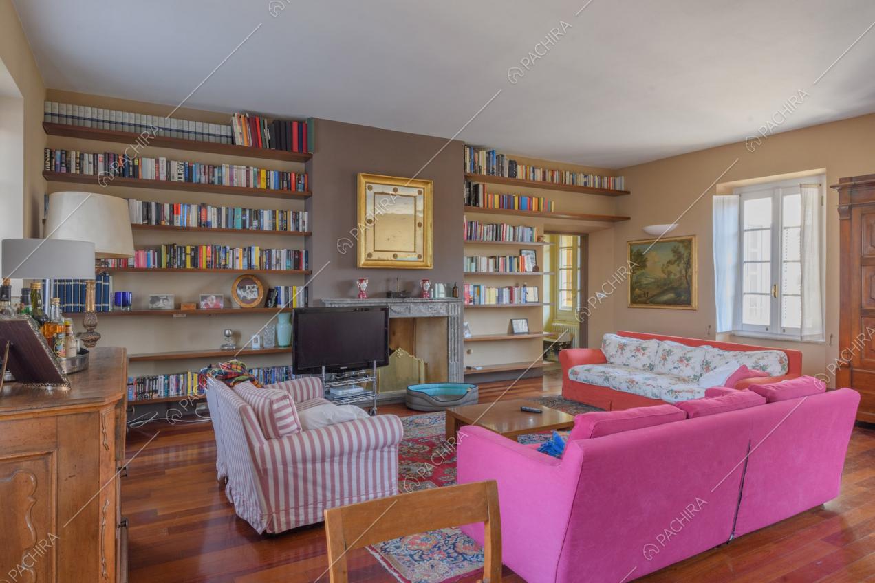 Luminosa zona living con pavimento in parquet, libreria e camino con cornice in marmo
